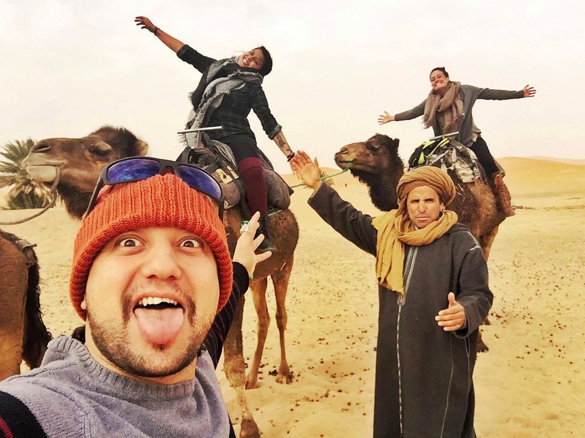 Waj and the Morocco Arukikata team taking a high-energy group selfie with guests in the Sahara Desert